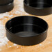 A black Matfer Bourgeat round non-stick tartlet pan.