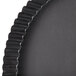 A close up of a Matfer Bourgeat fluted black tart pan with a removable bottom.