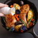 A person pouring Admiration Cooking Sherry into a pan of chicken.