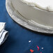 A close up of a cake on an Enjay black round cake drum on a table.