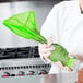 A person holding a Matfer Bourgeat green disposable pastry bag.