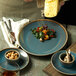 A person holding a Oneida Terra Verde Dusk porcelain plate with food.