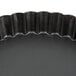 A black round Matfer Bourgeat non-stick fluted cake and tart pan with a wavy edge.