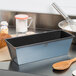 A Matfer Bourgeat flared bread loaf pan on a counter with a loaf of bread.