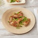 A Bamboo by EcoChoice round bamboo plate with food on a table.