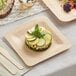 A Bamboo by EcoChoice square plate with vegetables on a table.