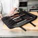 A chef putting Victorinox knives in a black tri-fold knife bag.