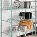 A Regency green epoxy wire drying rack shelf with pots and pans on it.