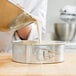 A person pouring cake batter into a Chicago Metallic aluminum springform cake pan.