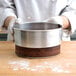 A person holding a Chicago Metallic aluminum springform cake pan with a cake inside.