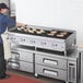 A man cooking food on a Cooking Performance Group gas radiant charbroiler.