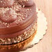An 8" gold laminated corrugated cake circle with a chocolate cake and nuts on top.