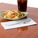 A plate of pasta and a drink on a Hoffmaster white dinner napkin.