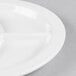 A close up of a Tuxton bright white china plate with three sections.