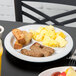 A Tuxton white china plate with three compartments holding breakfast food on a table.