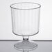 A clear plastic pedestal wine cup on a white surface.