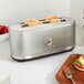 A KitchenAid Contour Silver long slot toaster with a plate of food and a fork on it.