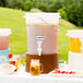 A white Choice beverage dispenser with a brown base filled with pink lemonade and lemon slices on a table.