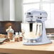 A KitchenAid lavender cream tilt head mixer on a wooden countertop.