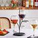 A Tablecraft black stand with three wine glasses on it.