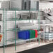 A metal wire rack with green shelves and metal posts.