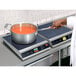 A chef using a Hatco countertop induction range to cook soup in a pot on a counter.