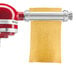 A KitchenAid pasta roller with a red handle.