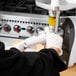 A person using a Weston Electric Meat Grinder to grind meat into a white plastic tube.