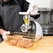 A man in a chef's uniform using a Weston Electric Meat Grinder to make meat.