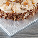 A frosted cake on a silver Enjay square cake drum.