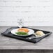 A black plastic room service tray with a plate of food on it.