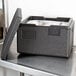 A black Cambro Cam GoBox sitting on a counter with clear plastic wrap inside.