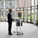 A man standing at a Luxor standing workstation with a printer on a shelf.