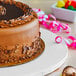 A chocolate cake on a white Enjay round cake drum.