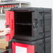 A woman opening a black and red Metro Mightylite storage box.