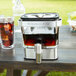 A KitchenAid cold brew coffee maker on a table with a glass container of brown liquid.