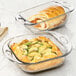 A clear glass square cake dish with food in it.