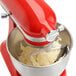 A red KitchenAid mixer with a Flex Edge Beater mixing dough in a bowl.