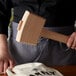 A person holding a Barfly wood ice mallet over a bag of ice.