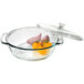 A clear glass Anchor Hocking round cake pan filled with vegetables and covered with a glass lid.