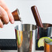 A person using an American Metalcraft Antique Copper Japanese Style Jigger to pour liquid.