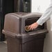 A person putting a cup into a Continental Colossus brown square trash can.