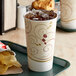 A tray with a Solo Symphony paper cup of soda and a bag of chips on a counter.