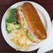 A sandwich and chips on a Cambro white polycarbonate plate.