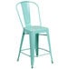 A mint green galvanized steel counter height stool with a slat back and drain hole.