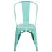 A mint green metal chair with a slat back and drain hole.