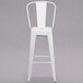 A white metal Flash Furniture bar stool with a backrest and a drain hole seat.