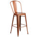 A brown metal outdoor bar stool with a copper seat and back with vertical slats and a drain hole.