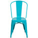 A teal blue metal chair with a slatted back and drain hole.