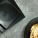 A stack of black square Luzerne Urban by Oneida porcelain plates with tortillas on one plate.